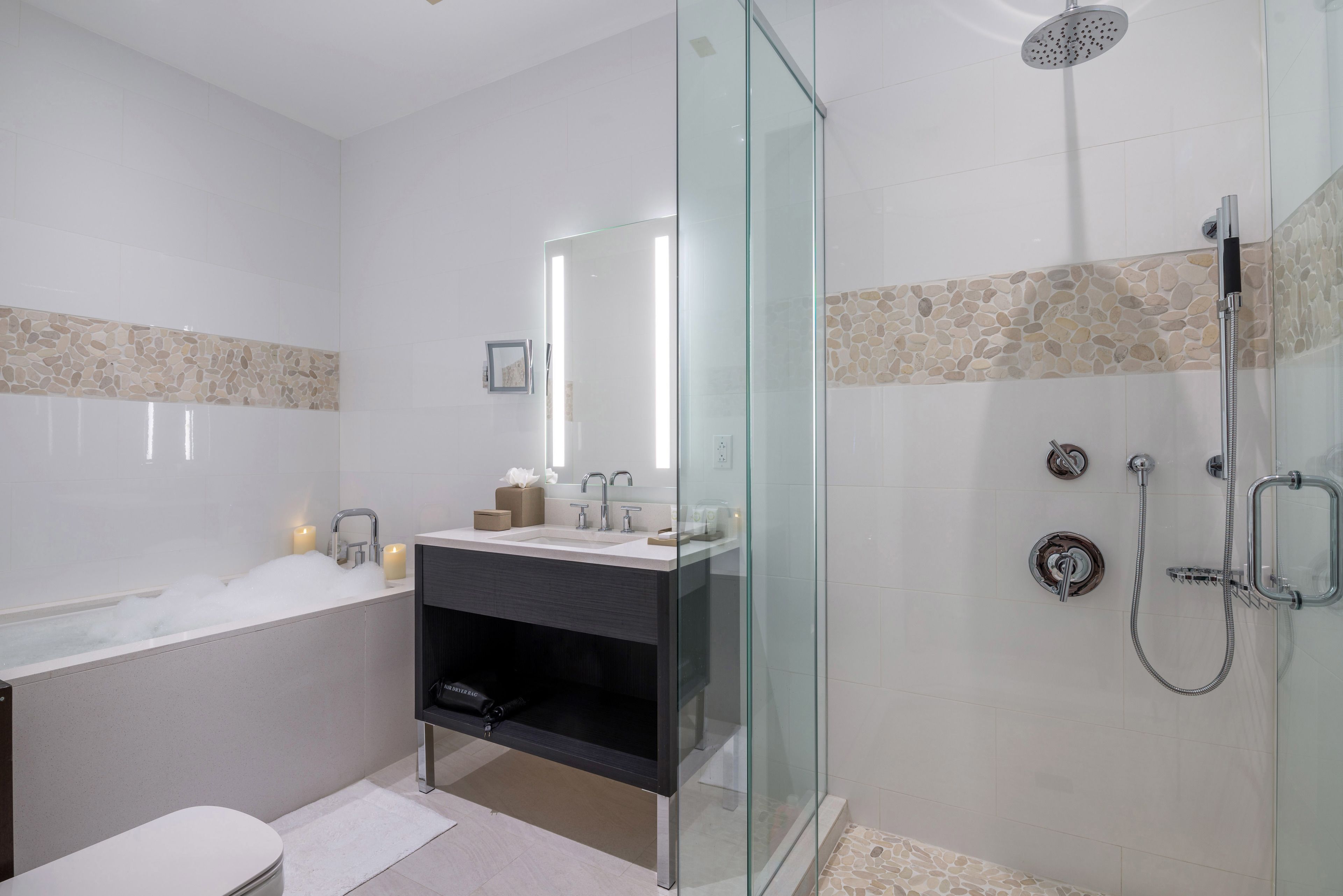 A modern bathroom with a glass-enclosed shower, a vanity with a mirror, and a bathtub.
