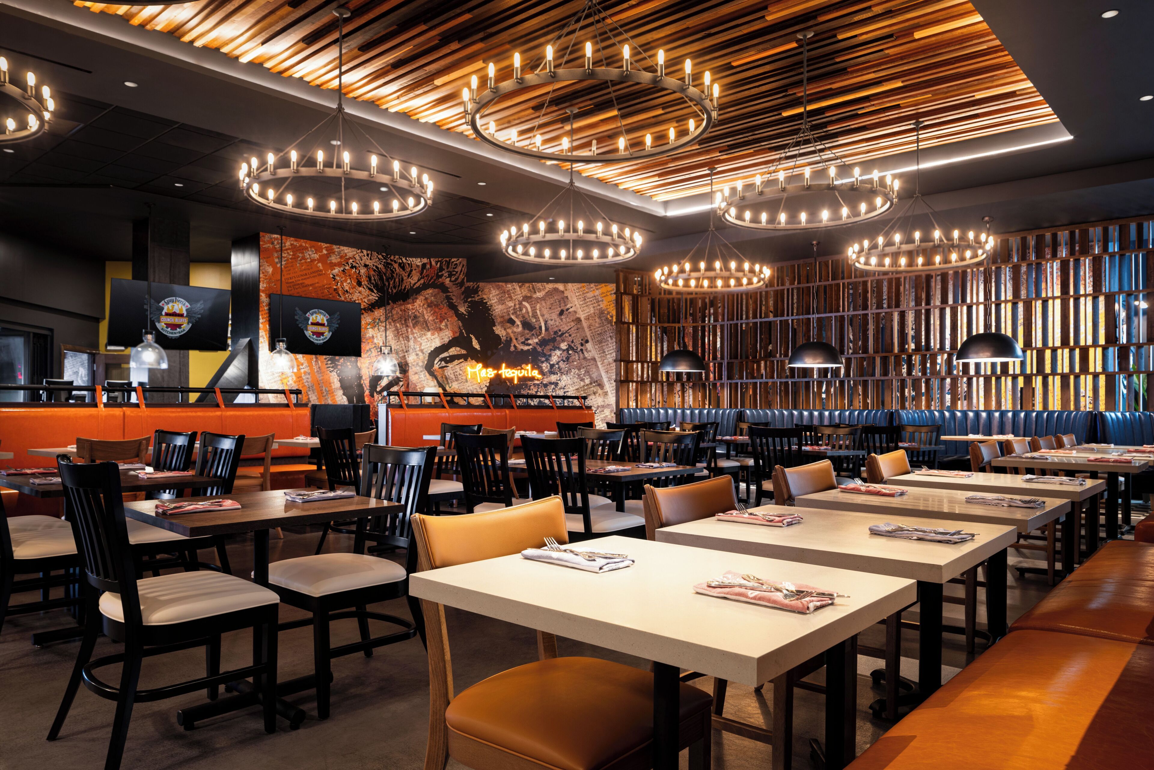 L’intérieur d’un restaurant, avec de nombreuses tables, des chaises et un design moderne au niveau du plafond.