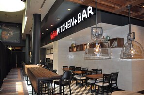 Interior de restaurant amb una barra de fusta llarga i diverses taules i cadires.