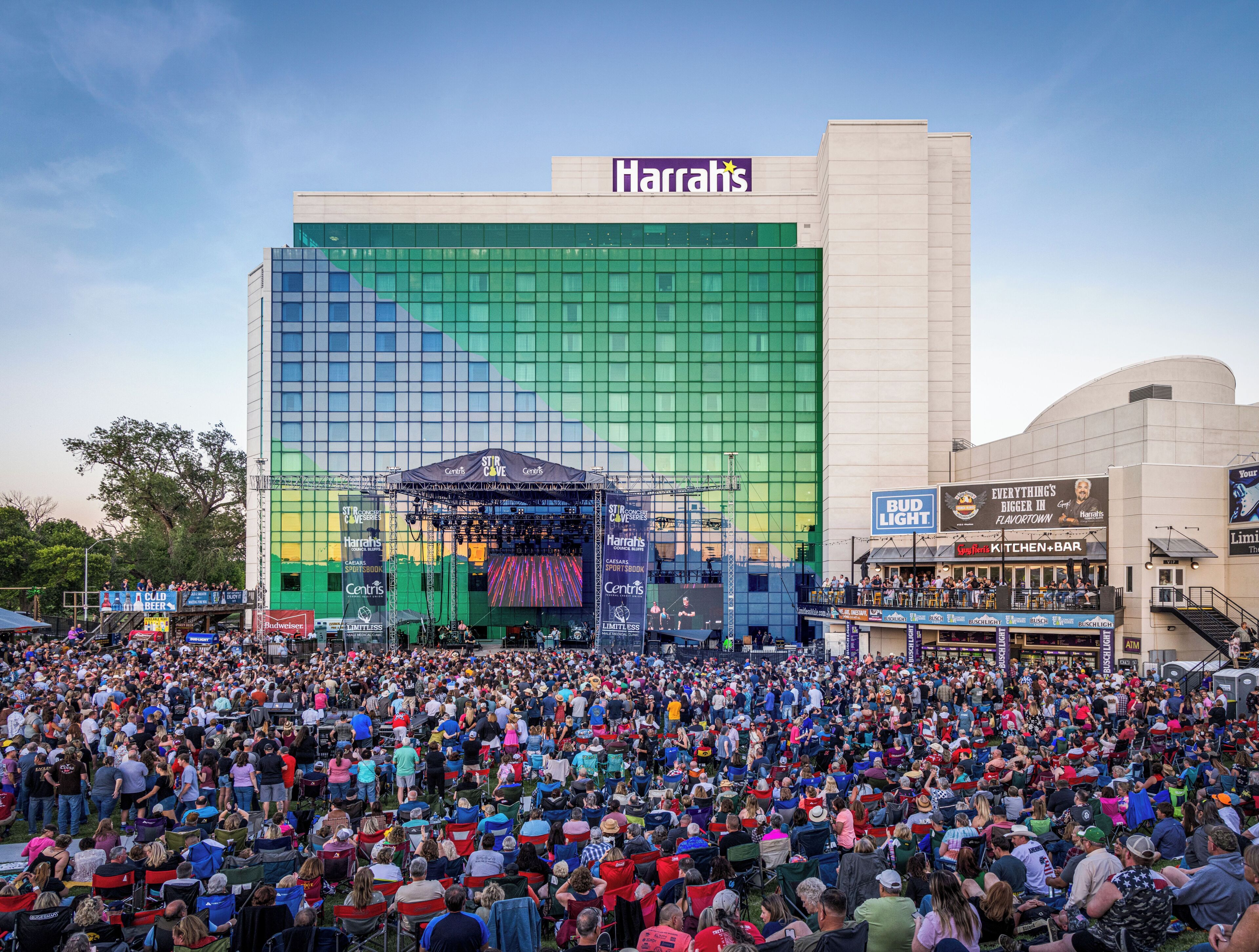 A large crowd gathered in front of a building with a Harrah's sign, indicating a casino or hotel.