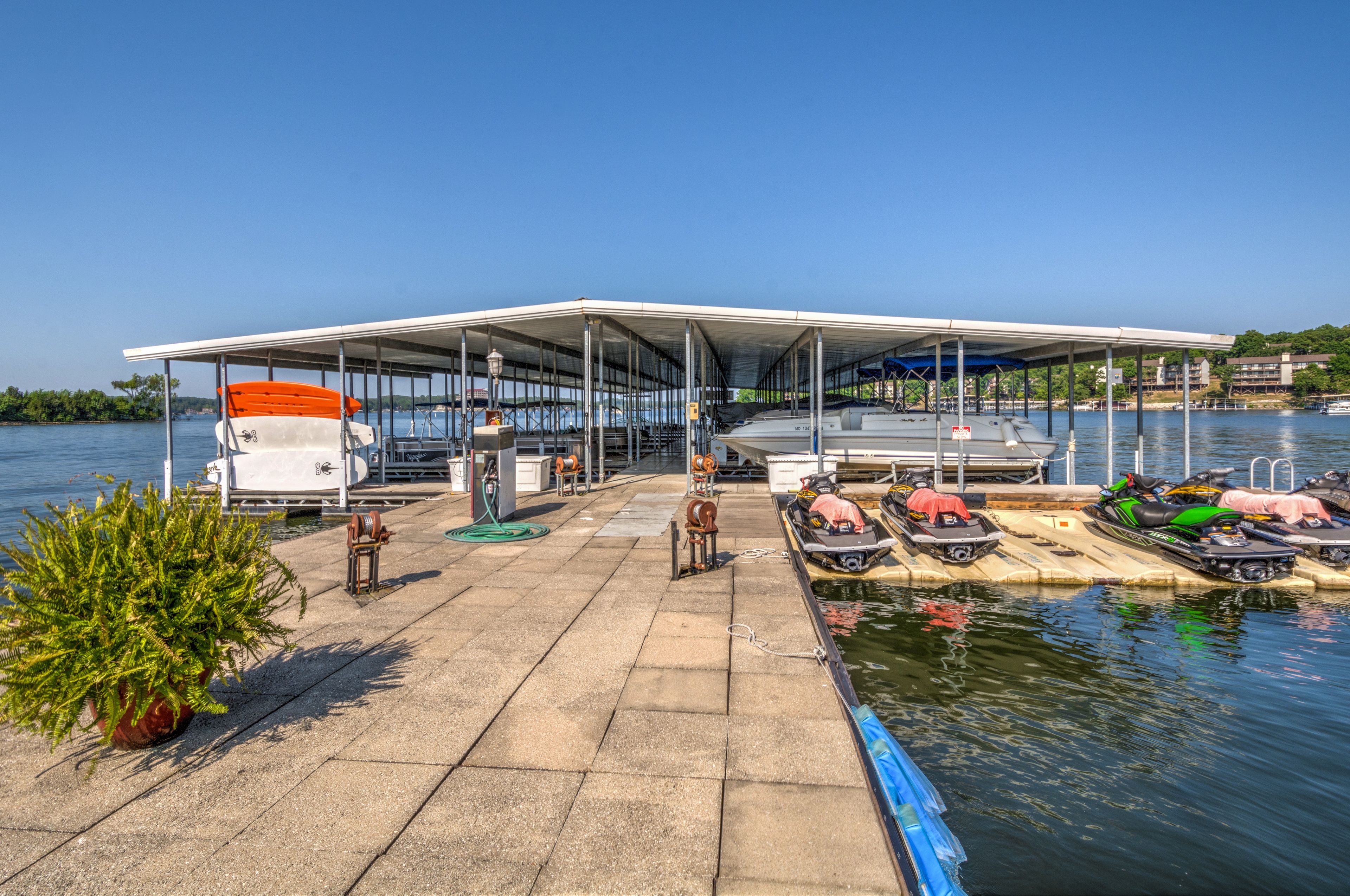 Un muelle cubierto con una fila de canoas y kayaks, una pequeña embarcación y una planta en maceta.