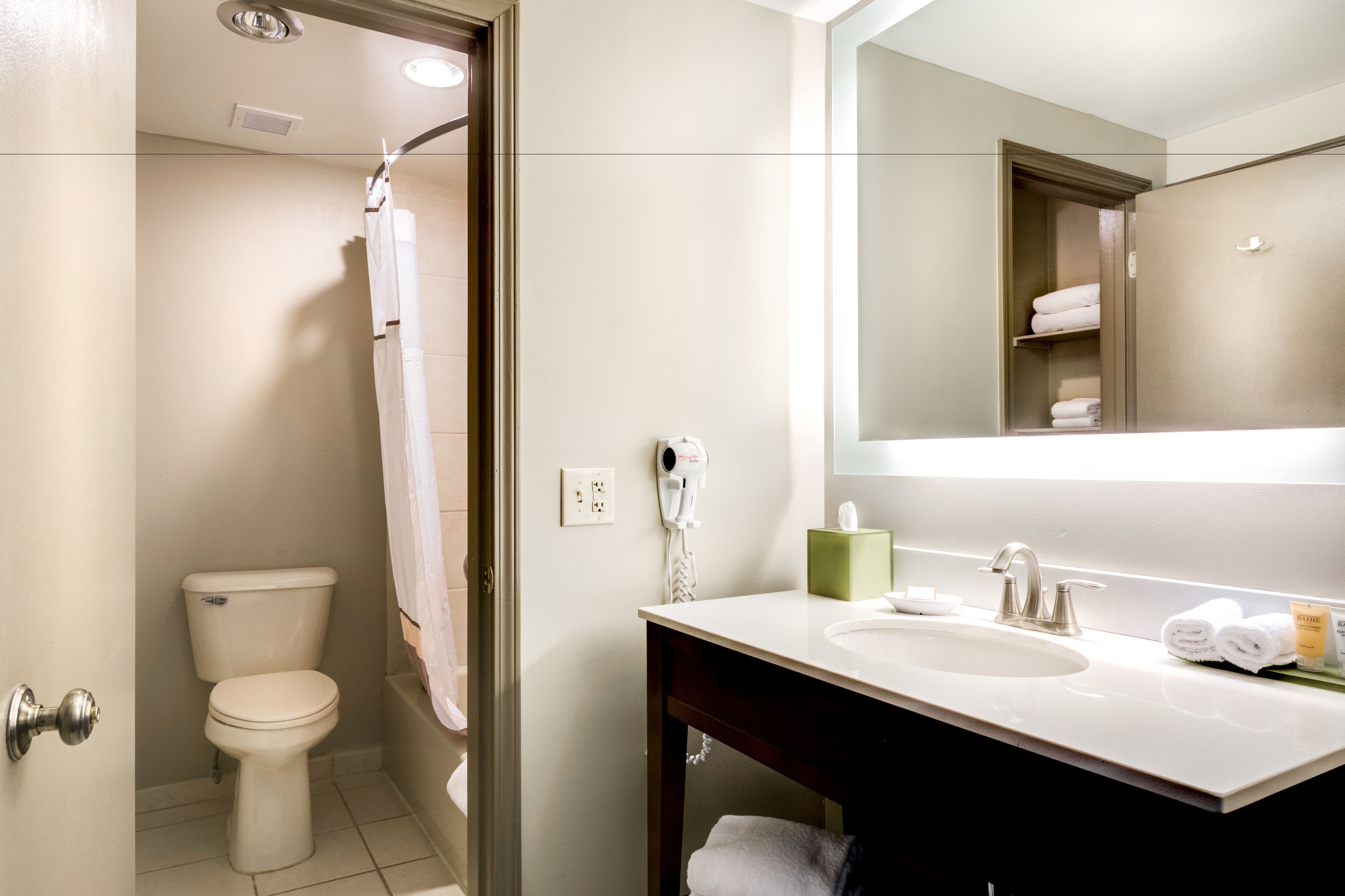 A bathroom with a toilet, a sink, a mirror, and a towel rack.