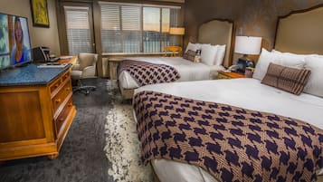 Une chambre d’hôtel avec deux lits, un bureau avec un ordinateur, une chaise et un téléviseur.