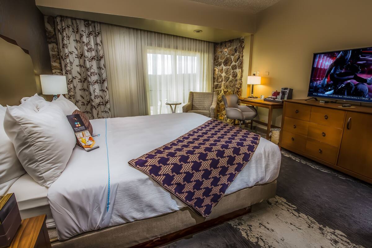 Une chambre d’hôtel dotée d’un grand lit, d’un bureau, d’une télévision et d’un mur décoratif en pierre.