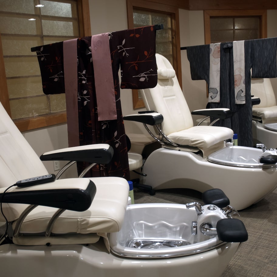A room with three reclining chairs, each with a foot bath and a remote control.