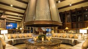 A lobby with a stone fireplace, seating area, and a view of the sky through the ceiling. - Lodge Of Four Seasons Golf Resort, Marina & Spa (Lake Ozark)