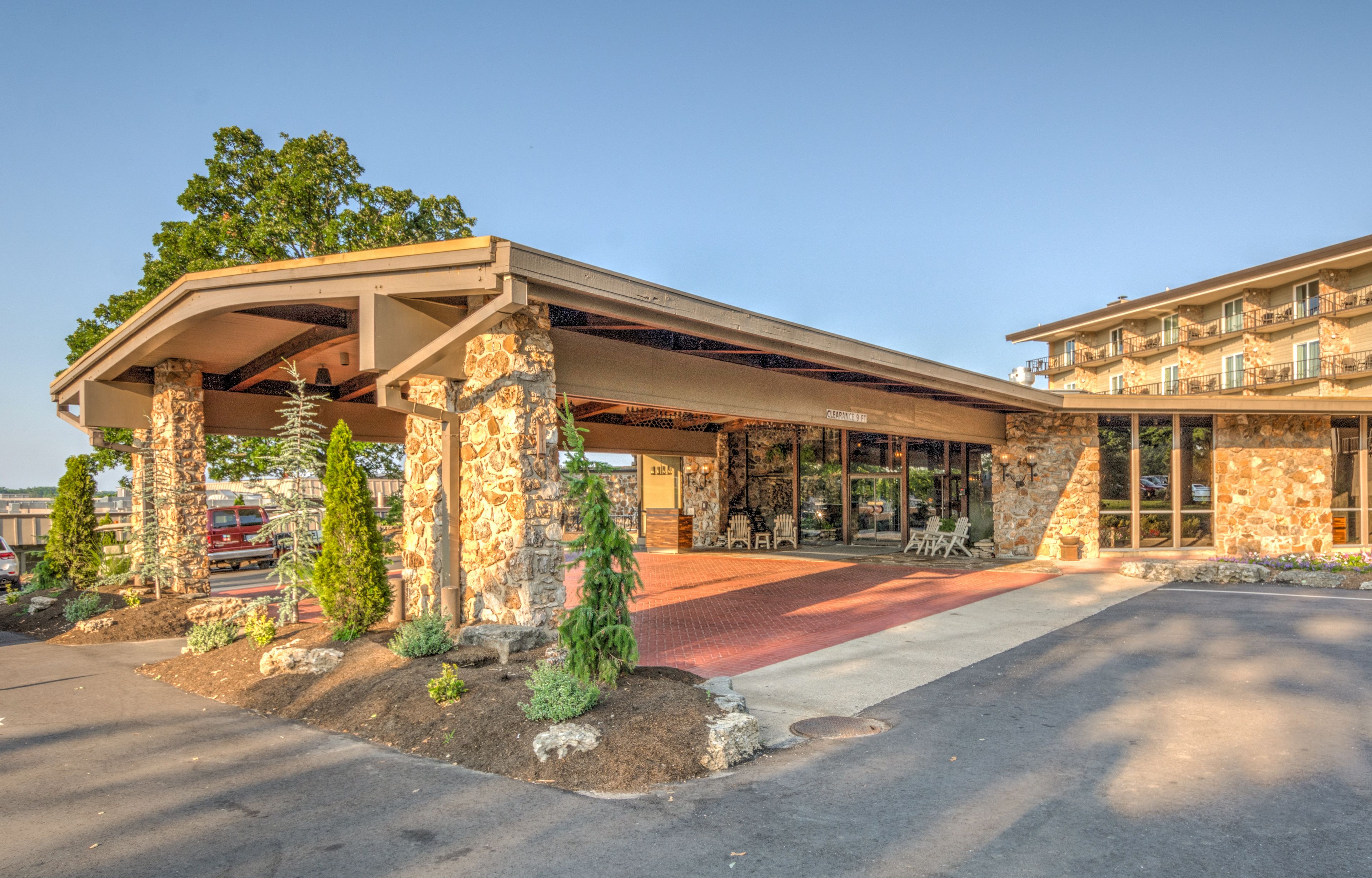 A hotel with a covered outdoor area, stone pillars, and a red carpet entrance.