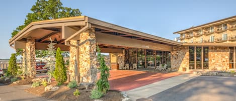 A hotel with a covered outdoor area, stone pillars, and a red carpet entrance.