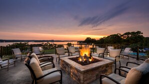 An outdoor seating area with a fire pit, chairs, and a view of a lake at sunset. - Lodge Of Four Seasons Golf Resort, Marina & Spa (Lake Ozark)