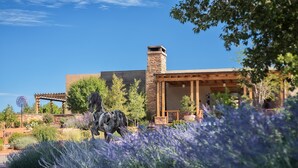 A modern house with a stone chimney, a pergola, and a sculpture in the garden. - Four Seasons Resort Rancho Encantado Santa Fe (Santa Fe)