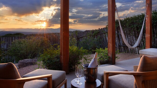 A wooden outdoor seating area with a view of the sunset, a hammock, and a bottle of champagne. - Four Seasons Resort Rancho Encantado Santa Fe (Santa Fe)