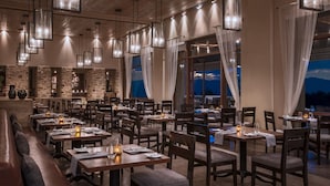 A restaurant with multiple dining tables, chairs, and hanging pendant lights. - Four Seasons Resort Rancho Encantado Santa Fe (Santa Fe)