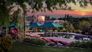 A pool area with lounge chairs and umbrellas, surrounded by greenery and buildings. - Four Seasons Resort Rancho Encantado Santa Fe (Santa Fe)