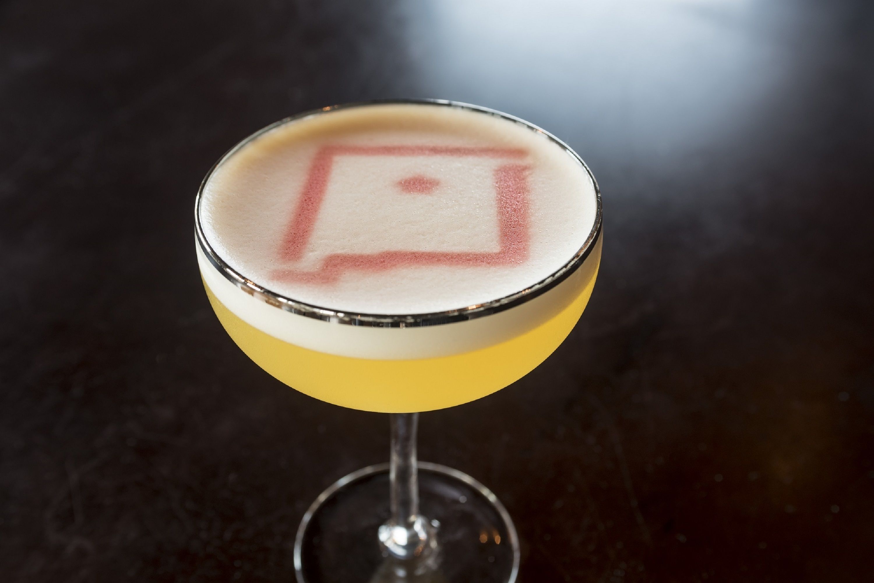 A cocktail in a martini glass with a frothy top.