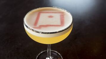 A cocktail in a martini glass with a frothy top.