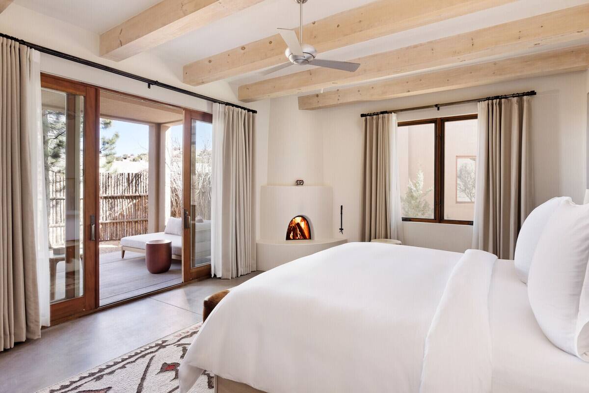 A spacious bedroom with a large bed, a ceiling fan, and a fireplace.