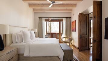A bedroom with a bed, bedside tables, a ceiling fan, a window with curtains, a chair, and a door.
