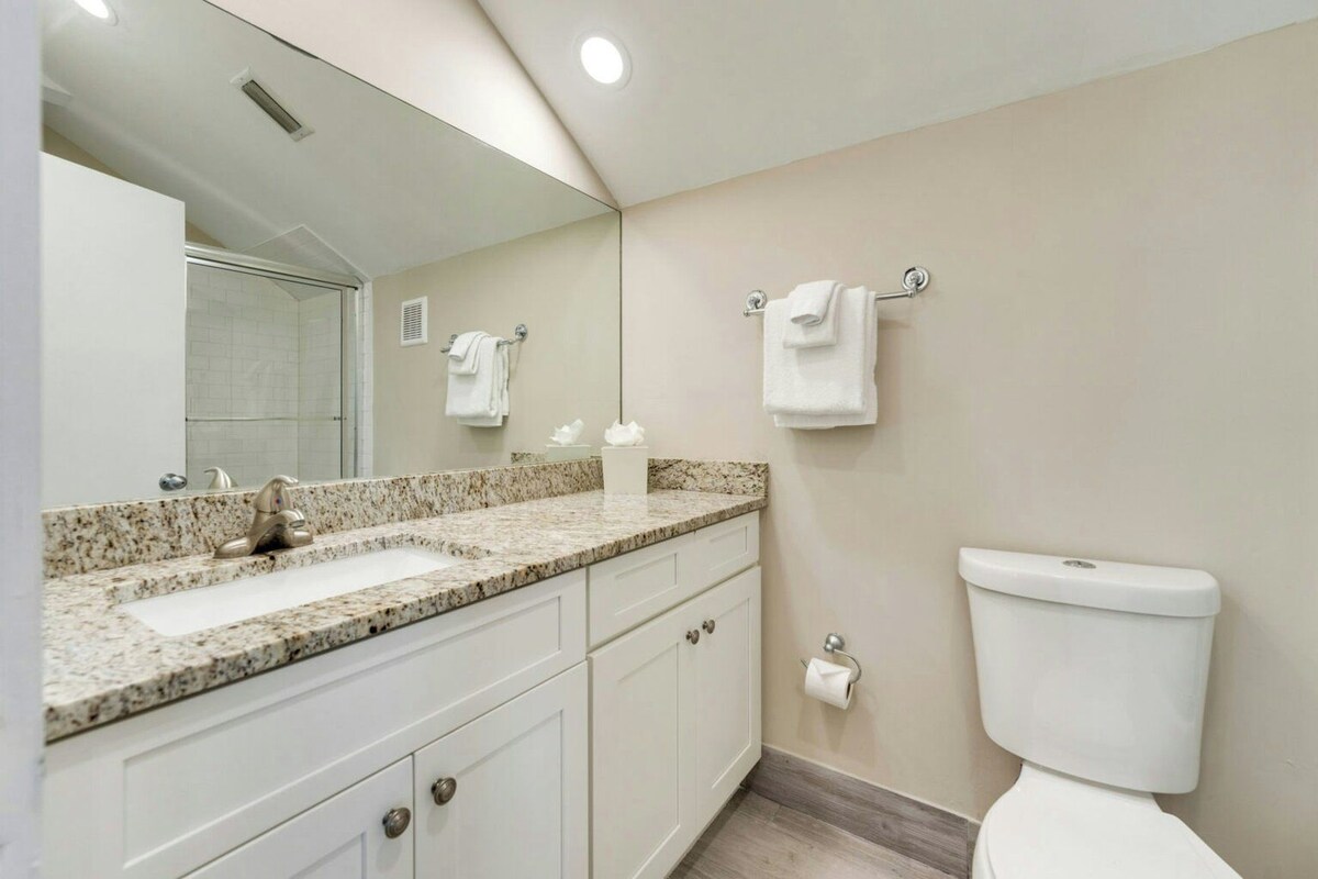 A bathroom with a sink, mirror, toilet, and towel rack.