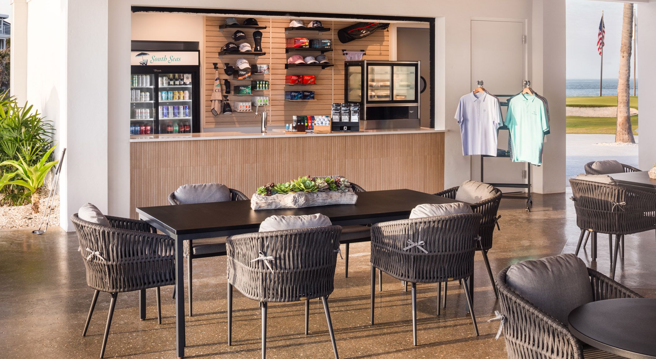 Een restaurant met een toonbank waarop diverse dranken en een assortiment golfpetten en accessoires staan uitgestald.