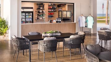 Een restaurant met een toonbank waarop diverse dranken en een assortiment golfpetten en accessoires staan uitgestald.