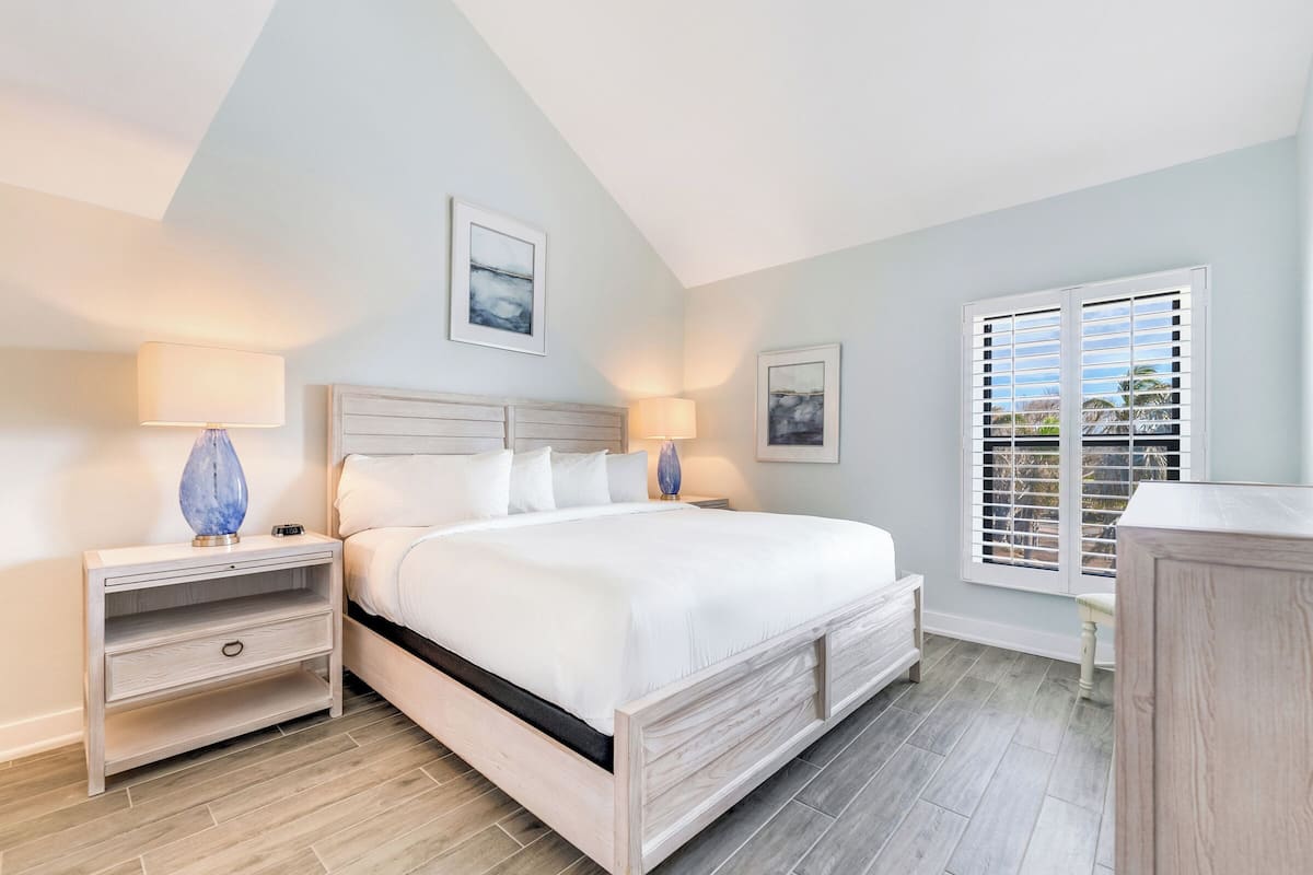 Une chambre à coucher avec un lit, des tables de chevet et une fenêtre avec des stores.