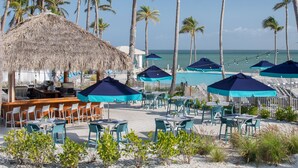 A beachside restaurant with outdoor seating, a pool area, and palm trees. - South Seas (Captiva)