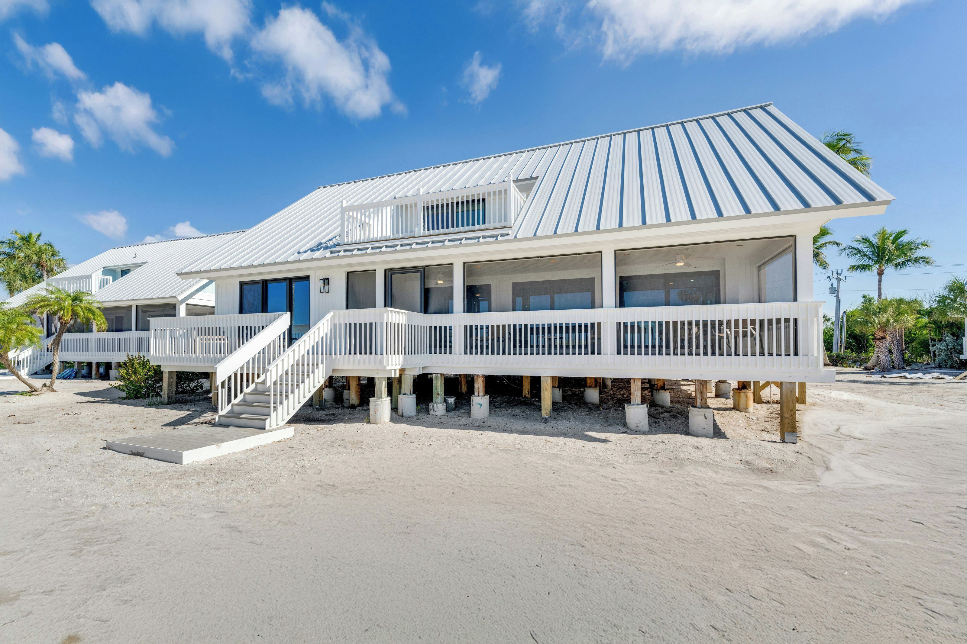 Een strandhuis met een groot terras, meerdere ramen en een trap naar de ingang.