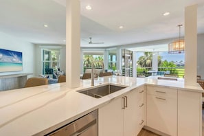 A modern kitchen with a large island, built-in appliances, and a view of the outdoors.