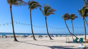 A beach with palm trees, string lights, and beach chairs. - South Seas (Captiva)