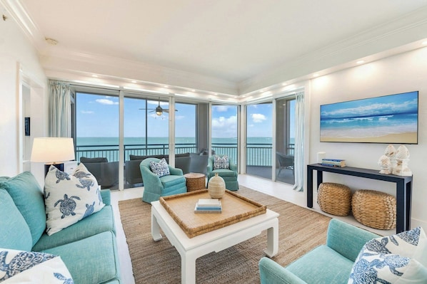A spacious living room with a view of the ocean, featuring a sofa set, a coffee table, and a console table with decorative items. - South Seas (Captiva)
