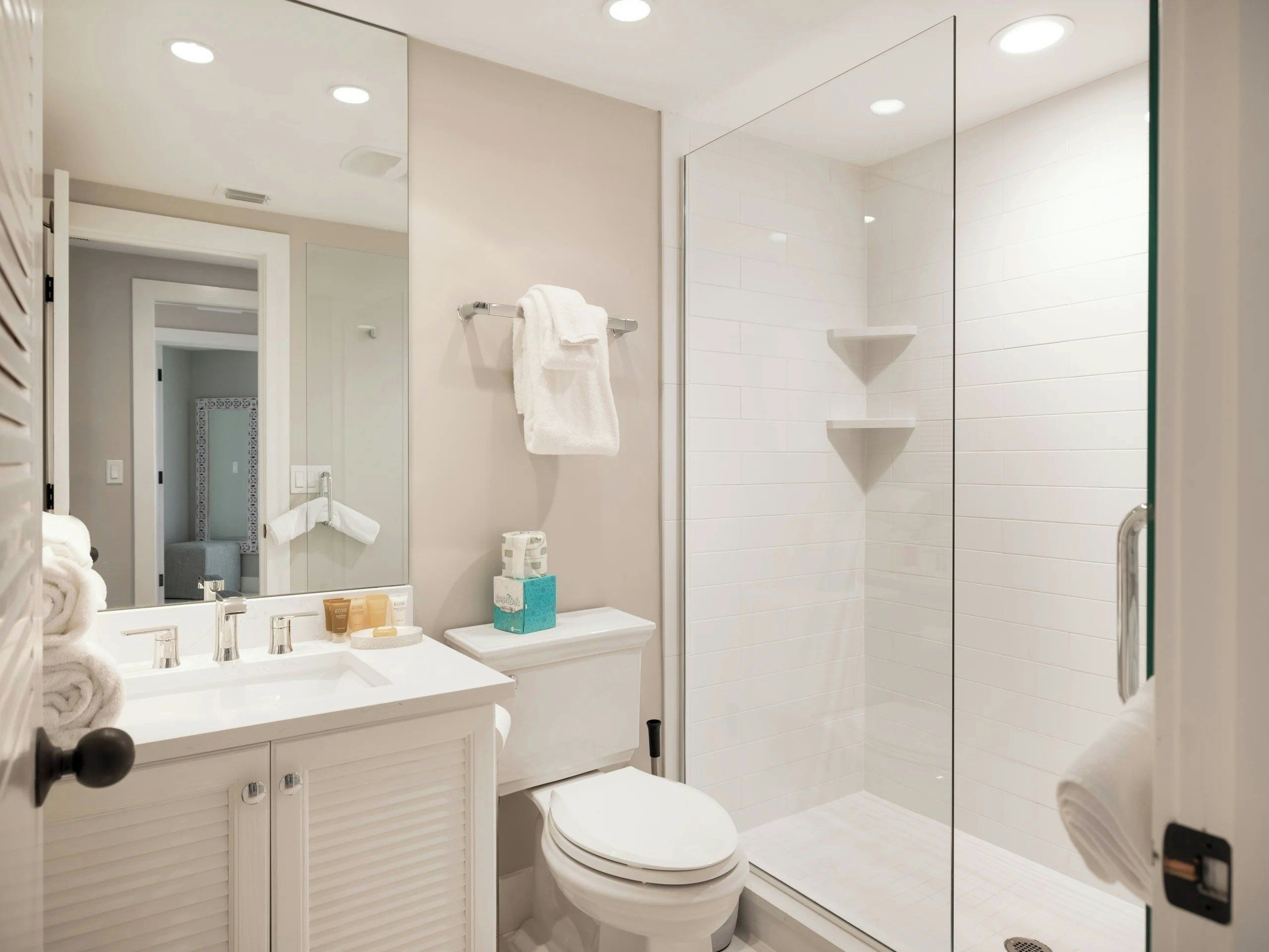 A modern bathroom with a glass shower enclosure, a white toilet, and a vanity with a mirror.