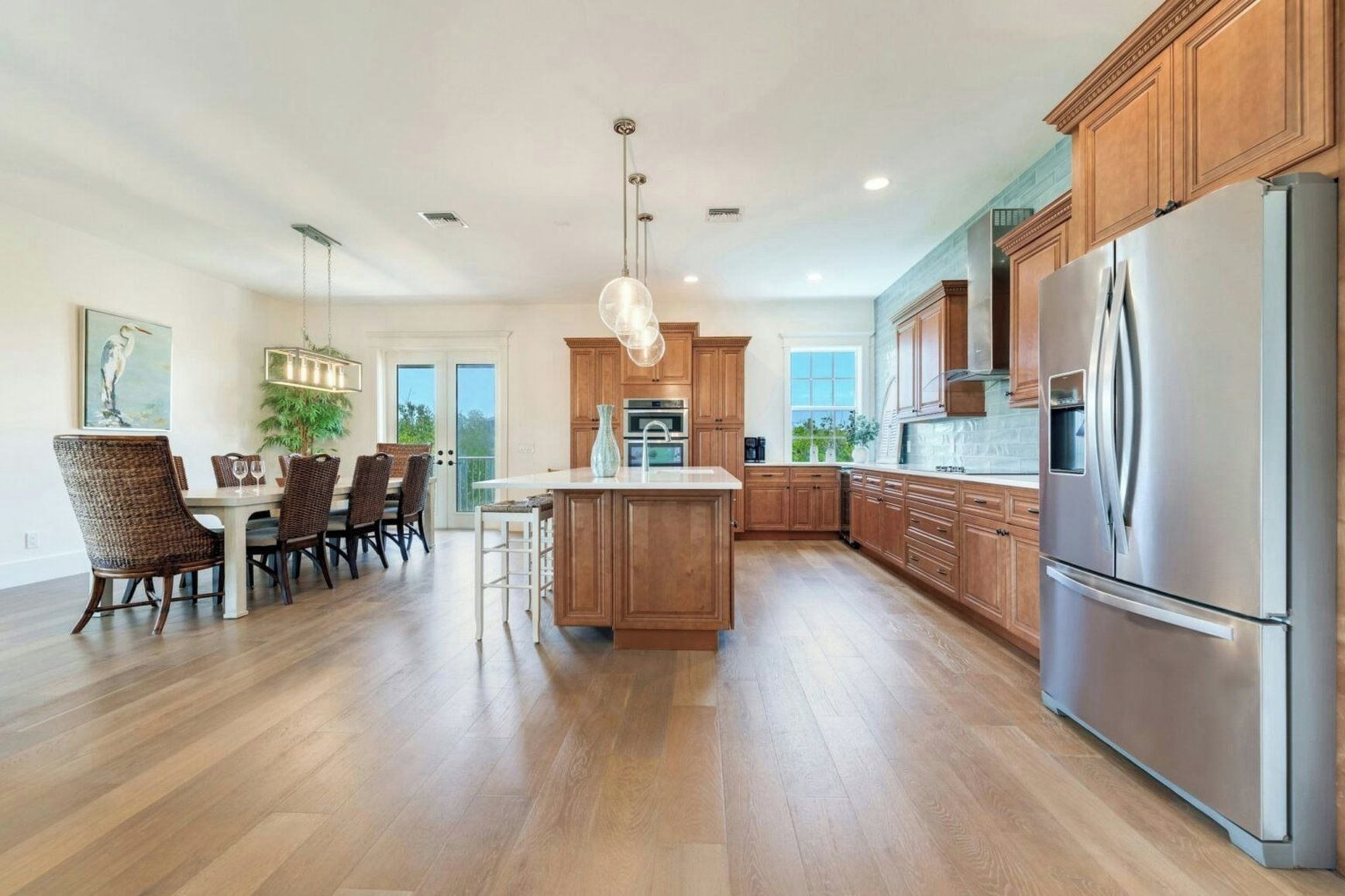 A modern kitchen with wooden cabinets, a stainless steel refrigerator, and a dining area with wicker chairs.