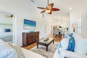 A spacious living room with a ceiling fan, a dining area, and a kitchen in the background. - South Seas (Captiva)