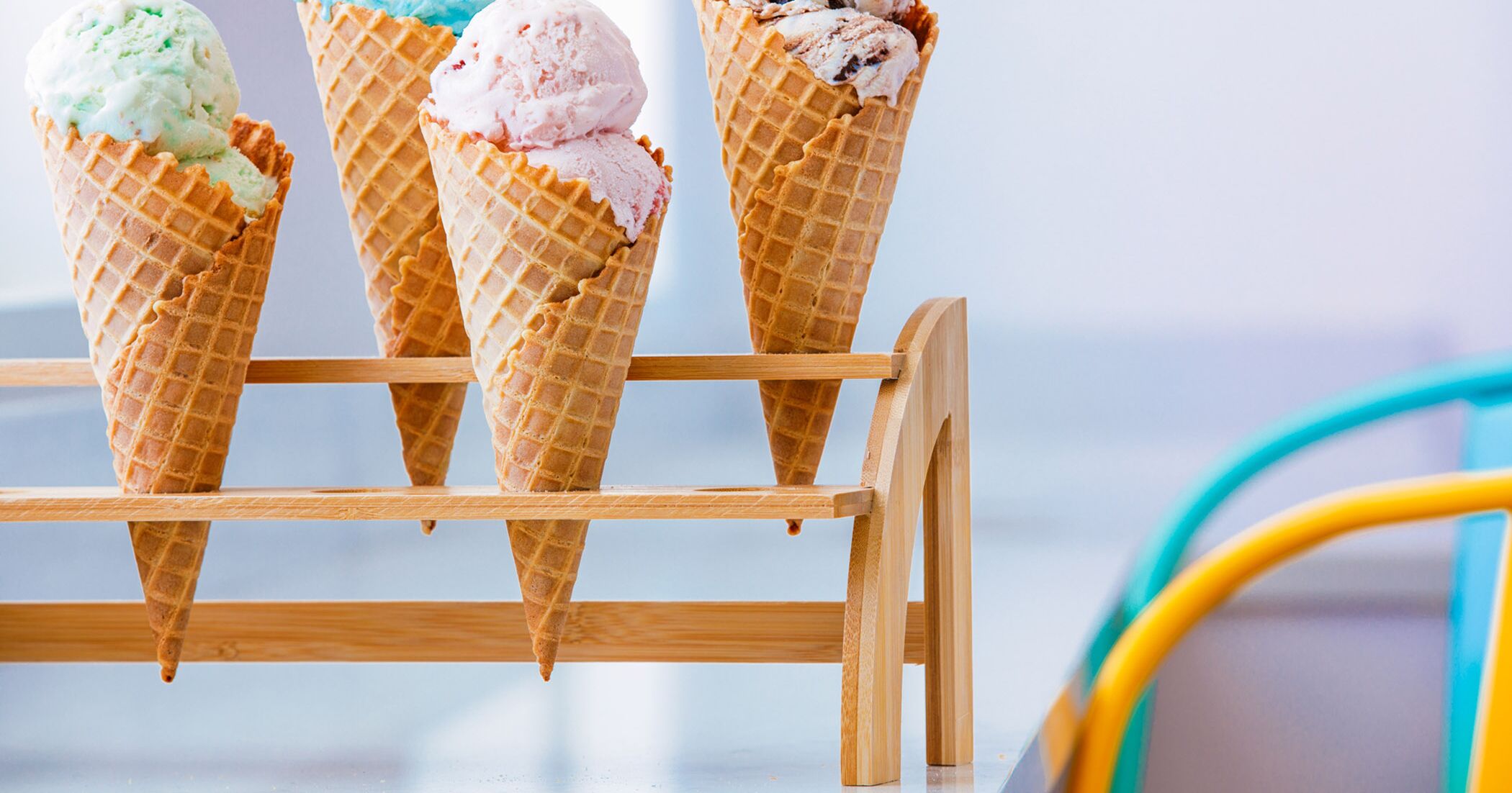 Four ice cream cones on a wooden stand.