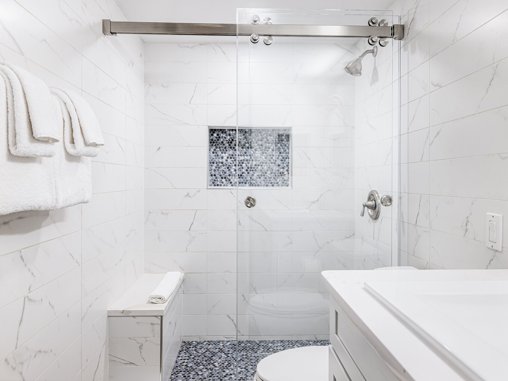 A modern bathroom with a shower, toilet, and sink.