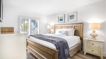 Une chambre à coucher avec un lit en bois, une literie blanche, deux lampes de chevet, une table de chevet et une fenêtre avec des stores.