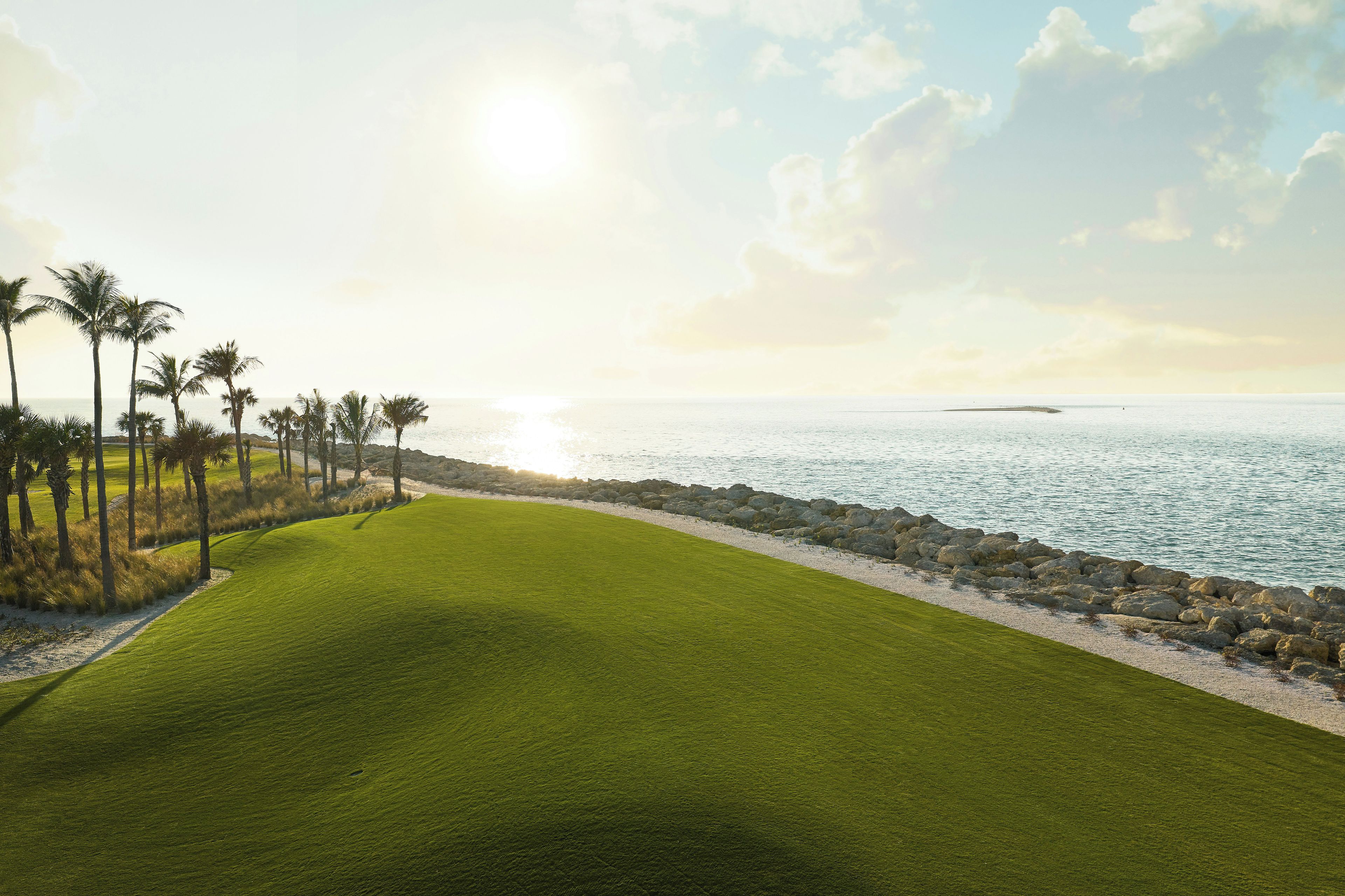 Camp de golf amb vistes a l'oceà i palmeres.