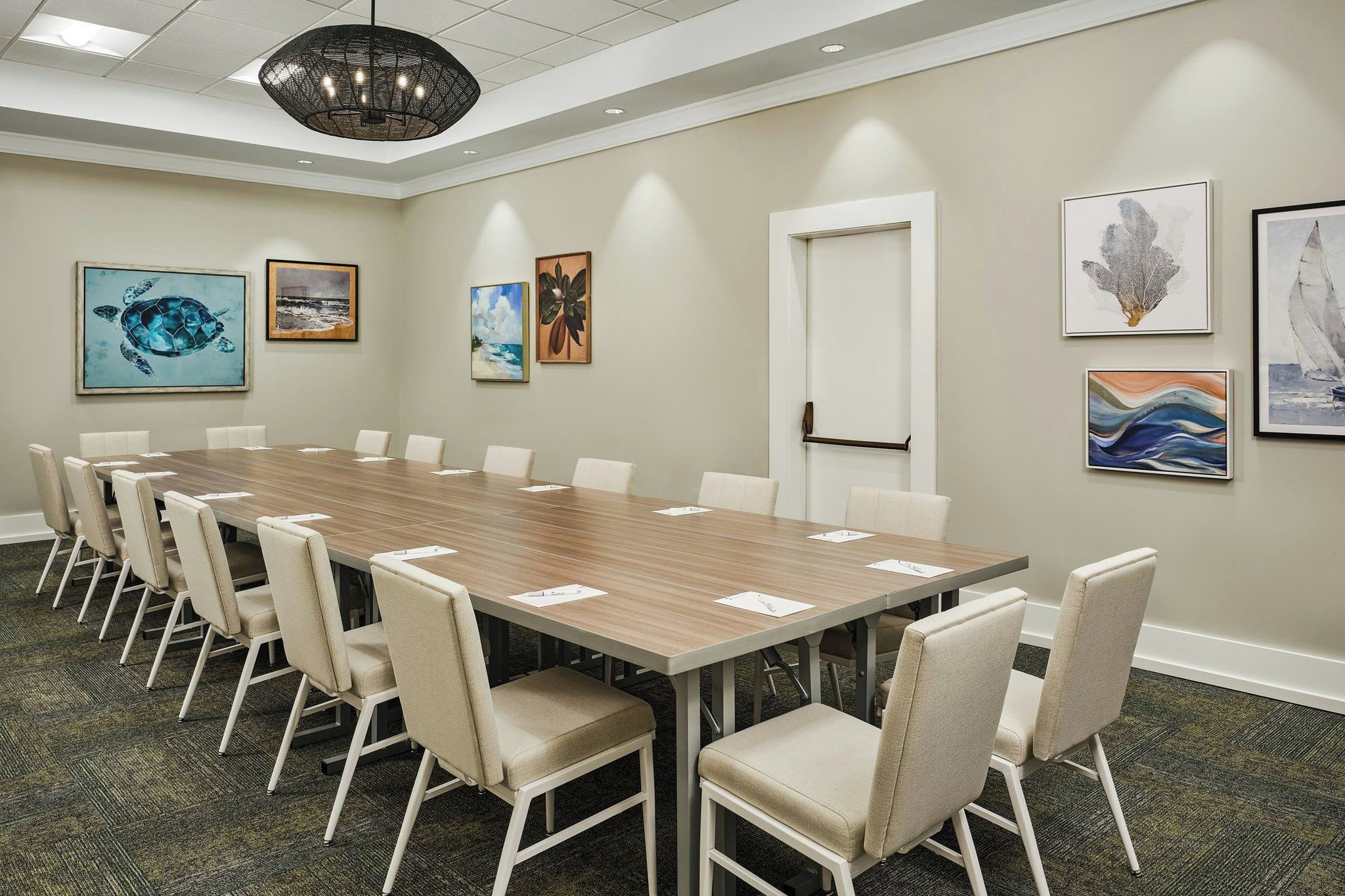 A conference room with a long table, chairs, and artwork on the walls.