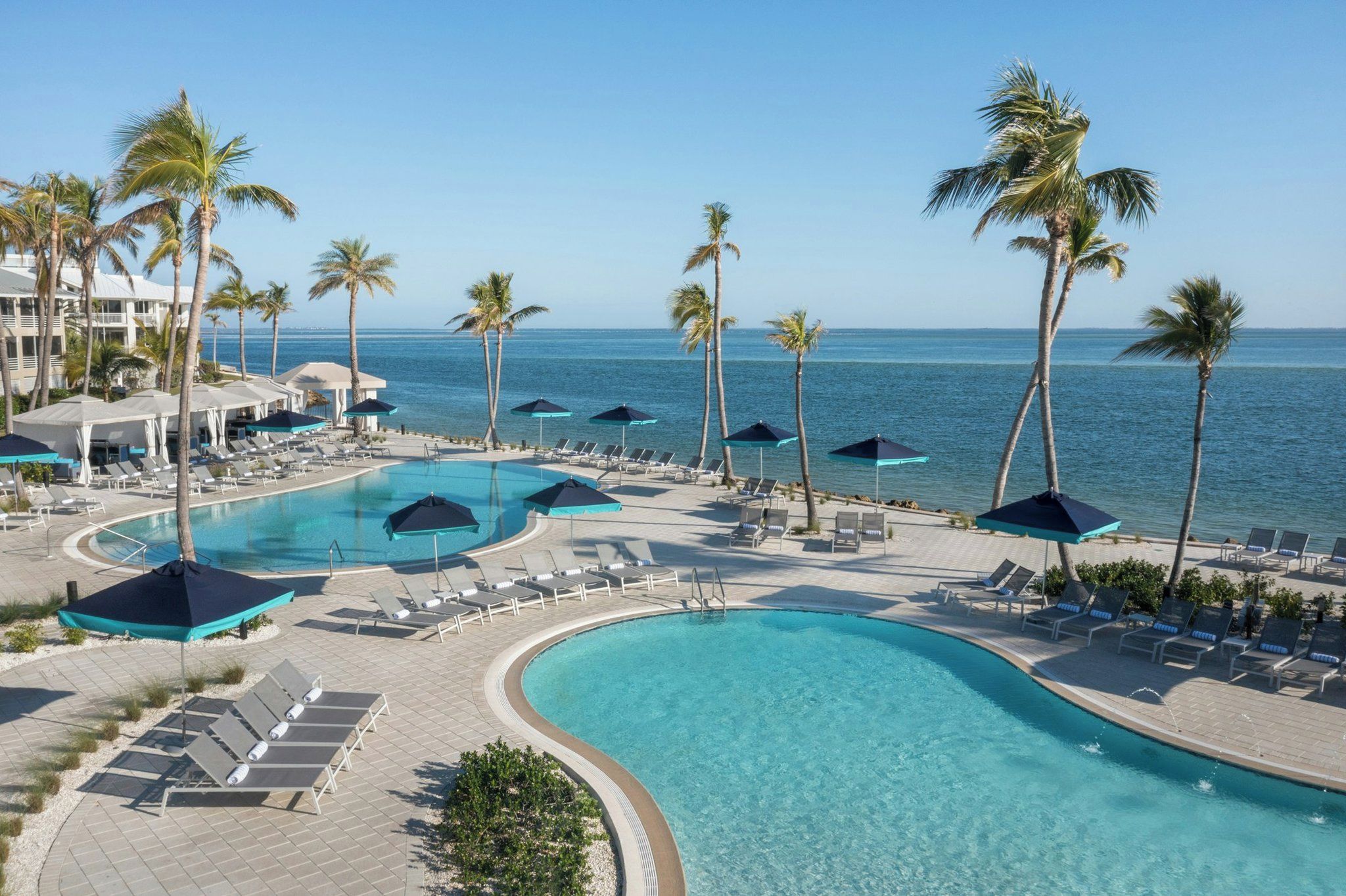 A resort with multiple swimming pools, sun loungers, and palm trees.