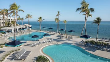 Un complexe hôtelier doté de plusieurs piscines, de chaises longues et de palmiers.