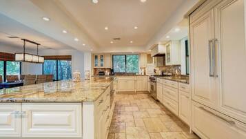 A spacious kitchen with a large island, white cabinetry, and a view through the windows.