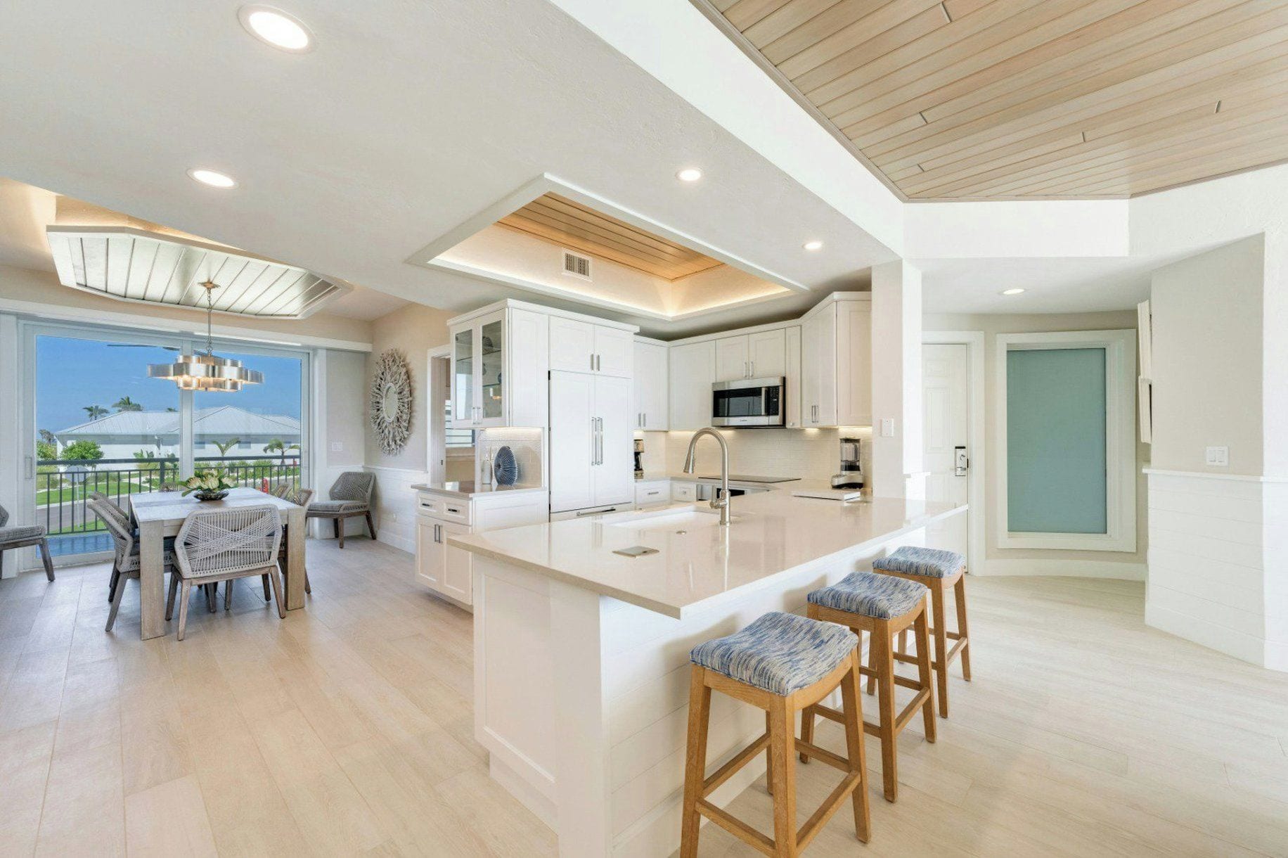 Una cocina moderna con una isla central, taburetes de bar y un comedor con vistas.