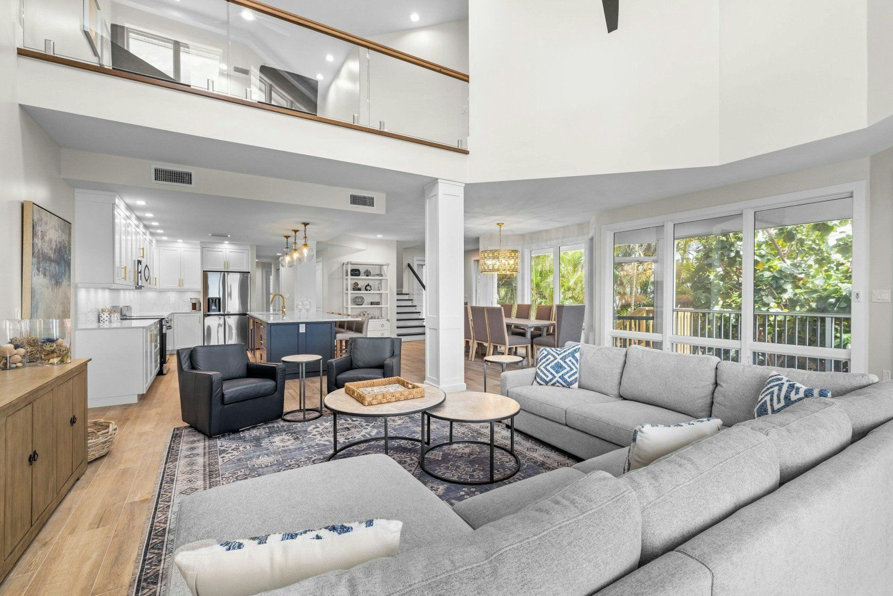 A spacious living area with a large gray sectional sofa, a coffee table, and a dining area with chairs.