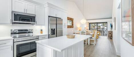 Una cocina moderna con armarios blancos, electrodomésticos de acero inoxidable y una isla central.