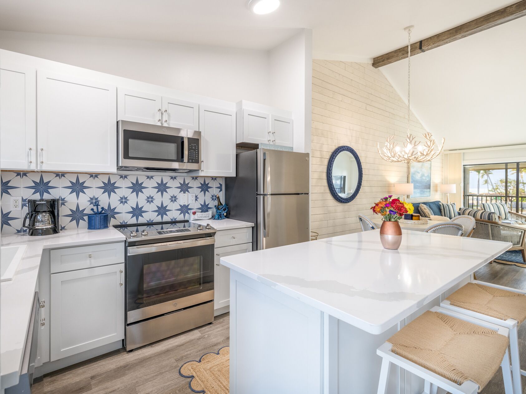 A modern kitchen with white cabinets, stainless steel appliances, and a blue star-patterned backsplash.