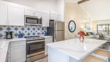 A modern kitchen with white cabinets, stainless steel appliances, and a blue star-patterned backsplash.
