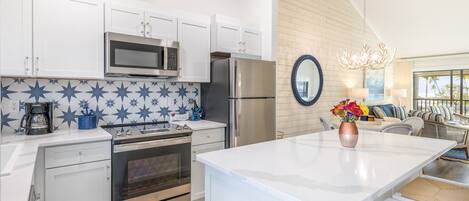 A modern kitchen with white cabinets, stainless steel appliances, and a blue star-patterned backsplash.