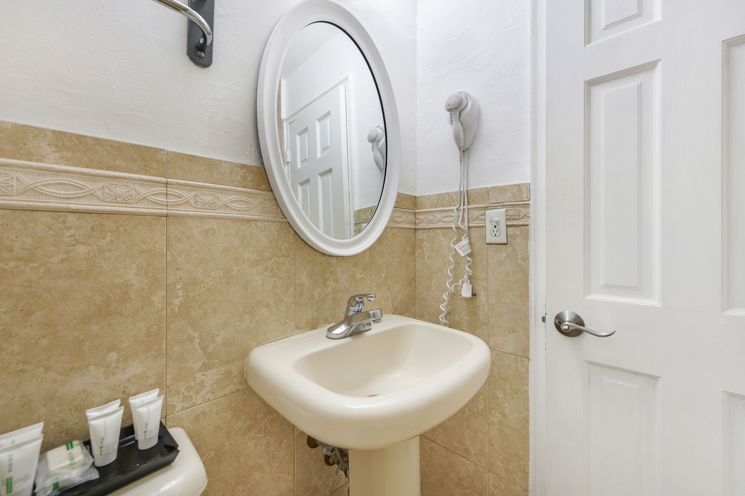 Un baño con lavamanos, espejo y secador de pelo.