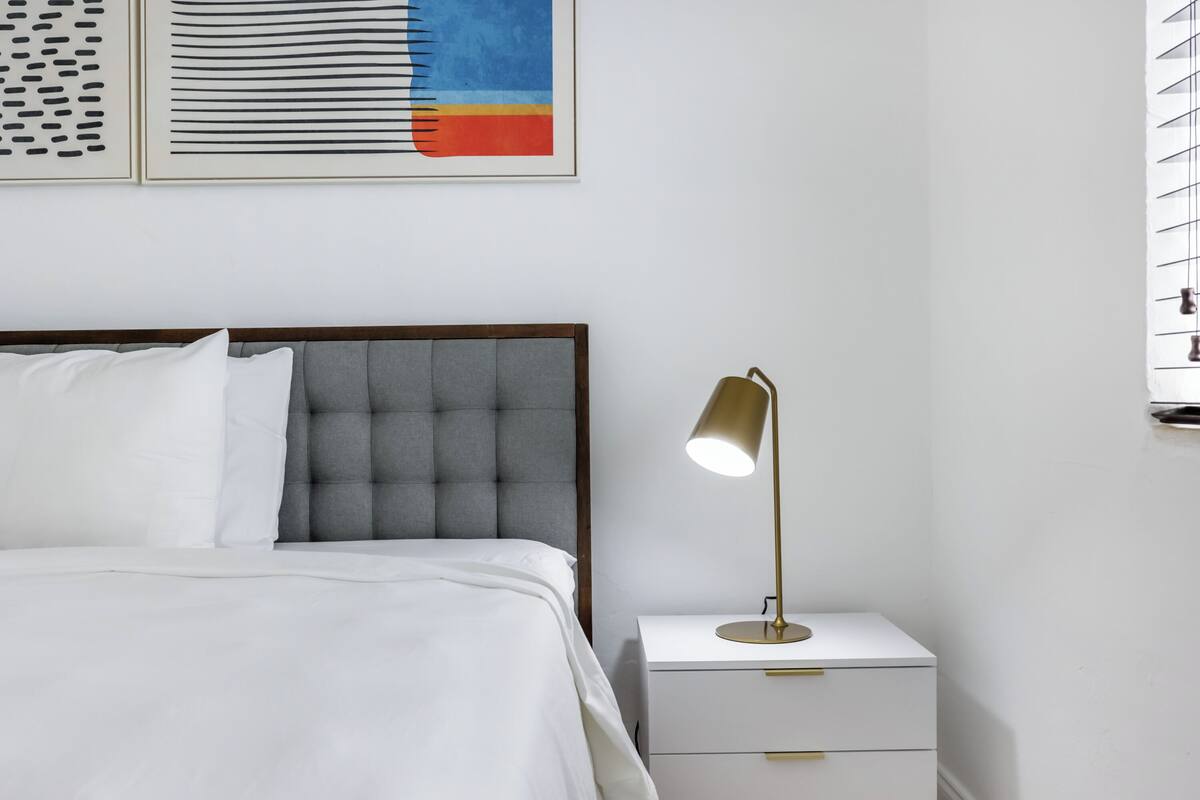 Una camera da letto ordinata con un letto, un comodino e una lampada.