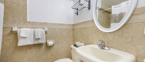 A bathroom with a toilet, sink, mirror, towel rack, and toiletries.